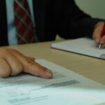 a man in a suit signing a document with a pen